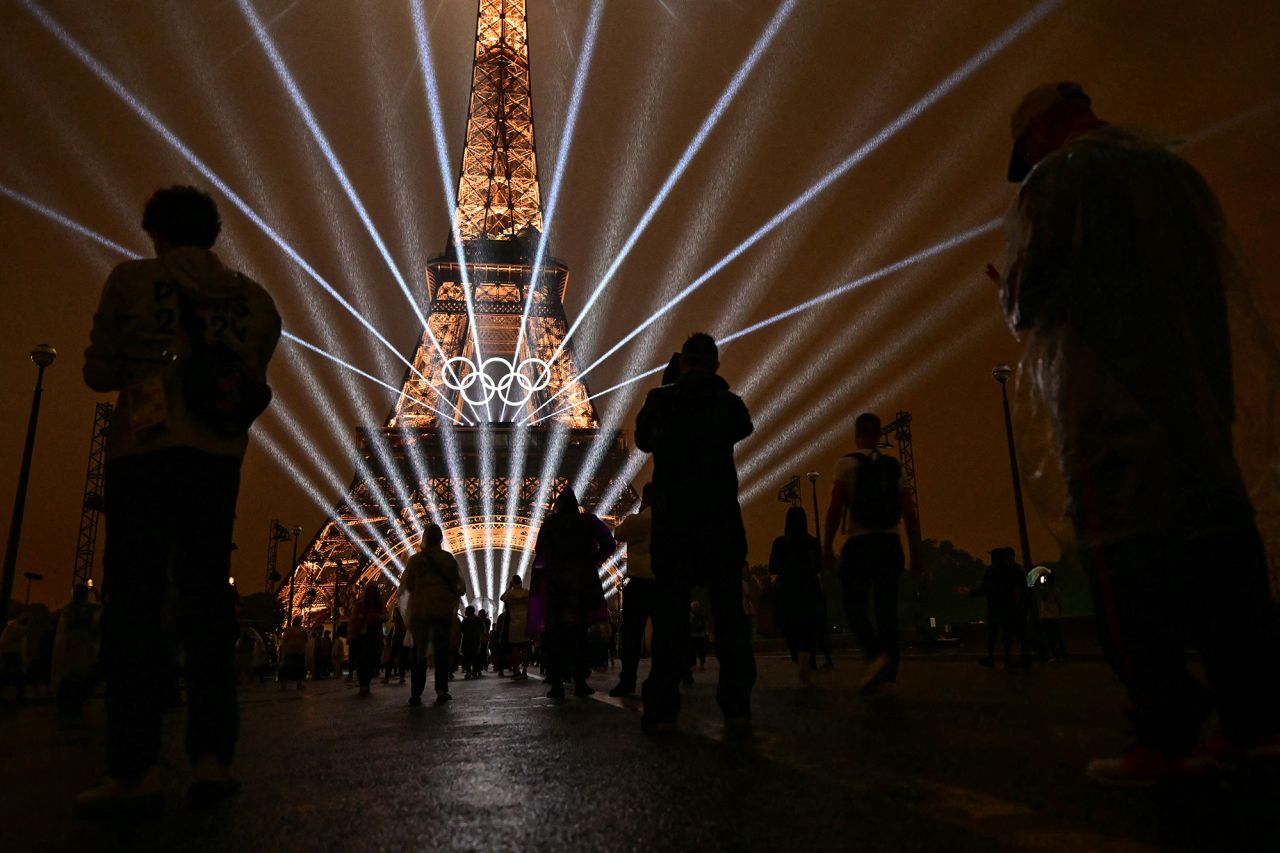 Attendees take pictures of the Eiffel Tower as lasers light up the sky during the opening ceremony of the Paris 2024 Olympic Games.