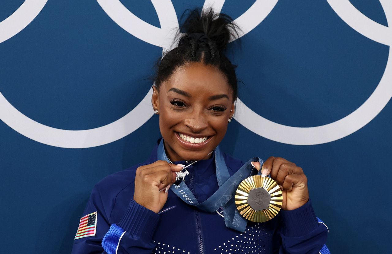 Gold medalist Simone Biles of Team United States poses with the Olympic Rings and a goat charm on her necklace during the artistic gymnastics women's all-around final medal ceremony on day six of the Olympic Games Paris 2024 at Bercy Arena on August 1.