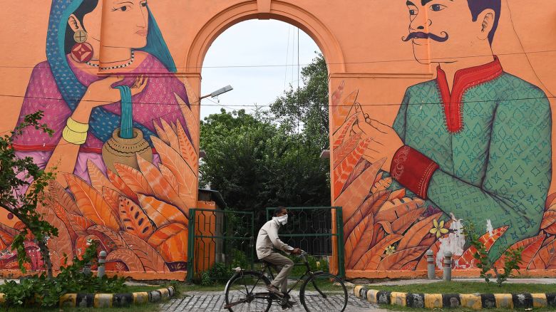 A man on a bicycle rides past a mural depicting a bride and a groom in New Delhi on August 31, 2020.