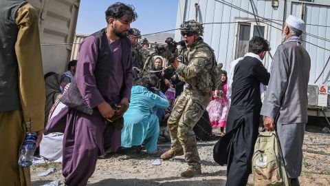 TOPSHOT - A US soldier (C) point his gun towards an Afghan passenger at the Kabul airport in Kabul on August 16, 2021, after a stunningly swift end to Afghanistan's 20-year war, as thousands of people mobbed the city's airport trying to flee the group's feared hardline brand of Islamist rule. (Photo by Wakil KOHSAR / AFP) (Photo by WAKIL KOHSAR/AFP via Getty Images)