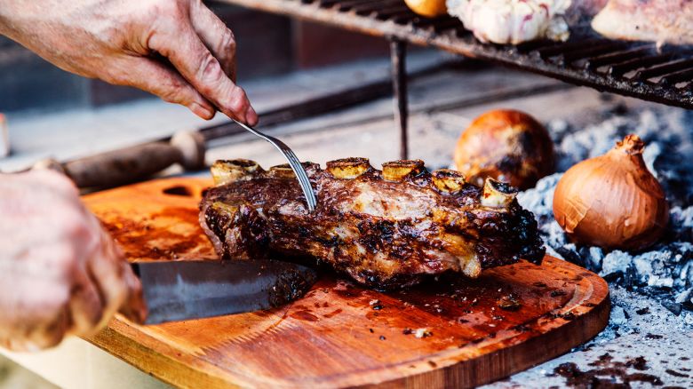 Argentine man cutting roast beef ribs. Traditional asado from Argentina. Barbecue.