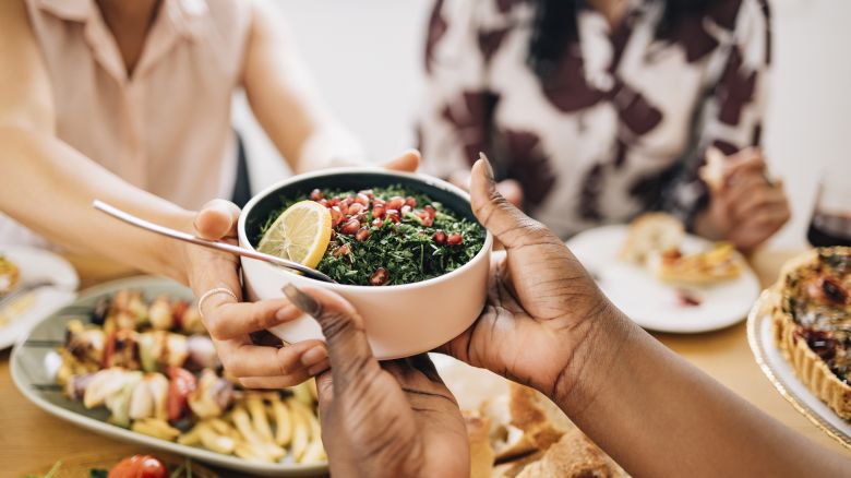 A cropped photo of an anonymous African-American female holding a bowl of  healthy salad.