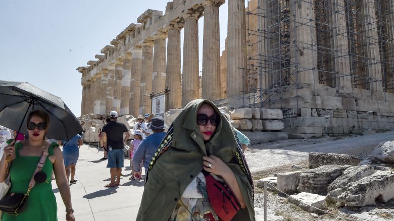 ATHENS, GREECE - JULY 20: Atop the Acropolis ancient hill, a tourist protect her self from burning sun during a heat wave on July 20, 2023 in Athens, Greece. The Acropolis of Athens and other archaeological sites in Greece announced reduced opening hours due to the heatwave conditions. Parts of Europe continue to experience extreme conditions of the Cerberus heatwave, dubbed Charon. (Photo by Milos Bicanski/Getty Images)