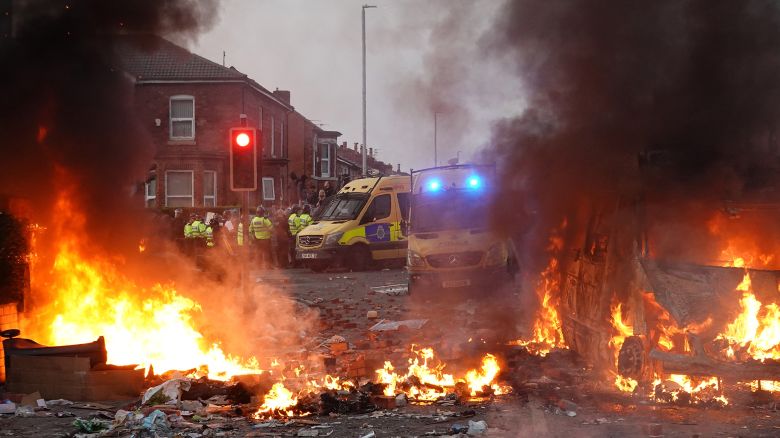 Police hold back rioters near a burning police vehicle after disorder broke out on July 30, 2024, in Southport, England.