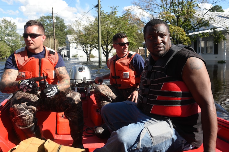 A Coast Guard boat crew assists Bernard Jones (right) in safely getting to his house Tuesday, September 18, in Pollocksville, North Carolina. Jones and his family left their home before Hurricane Florence flooded the town, leaving many buildings completely submerged.