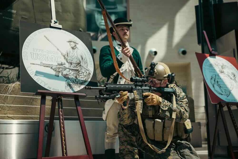 A soldier aims an automatic weapon to the left next to a poster of a coin design, while another soldier in historical gear stand behind.
