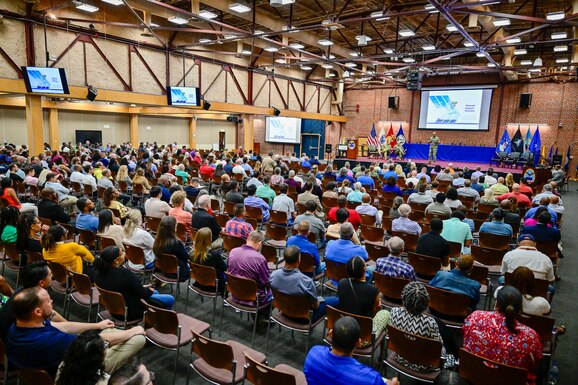 A briefer talks to a full conference center