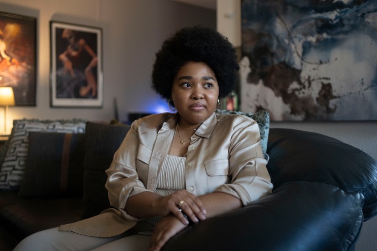 A portrait of Genesis Jones sitting on her sofa in her home