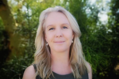 Woman smiling in front of trees.