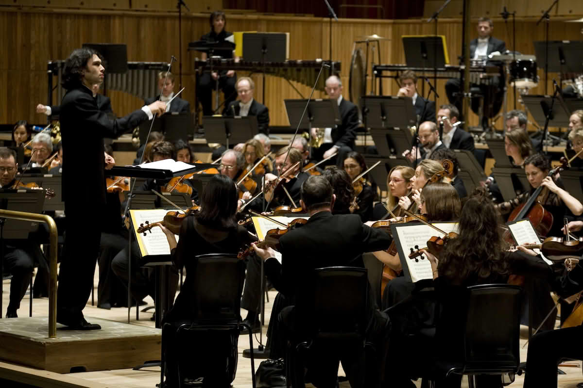 En dirigent foran et orkester som spiller klassisk musikk.