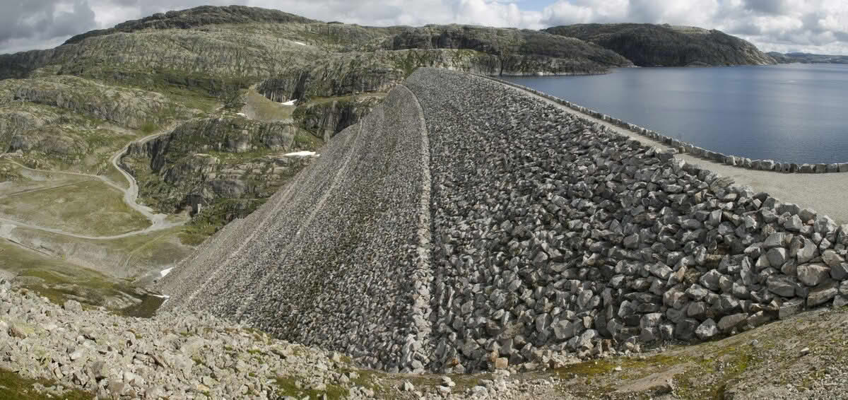 Et stort vann som er demmet opp av en enrom mur av stein.