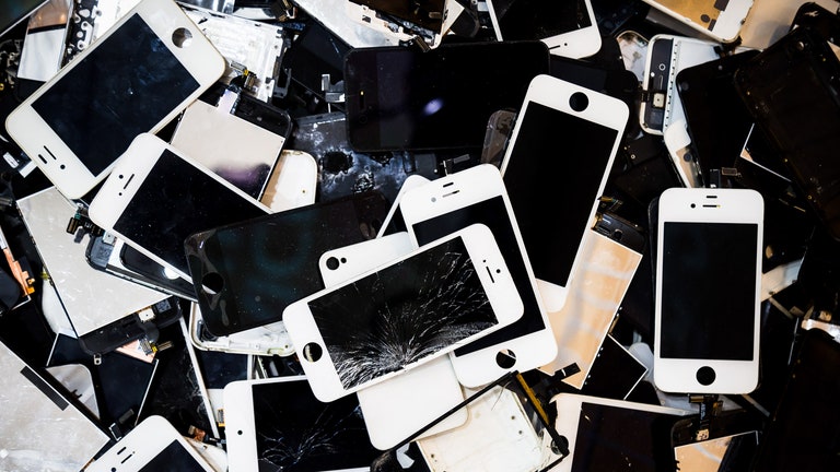 A pile of broken smartphones with cracked screens