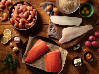 Overhead view of raw seafood in bowls and on plats eggs lemons potatoes and other ingredients