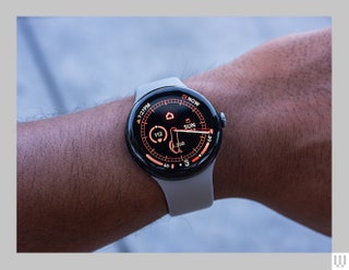 Person's wrist wearing a smartwatch with the screen showing time date and health metrics such as heart rate and number...