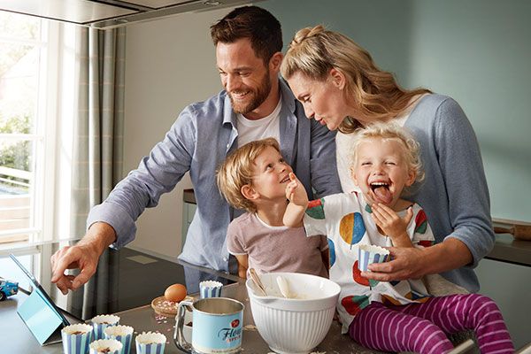 A family on the sofa happily using the Home Connect app.