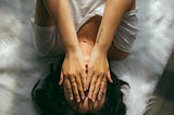 Woman lying down with her hands covering her face