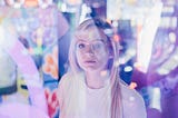 A woman standing behind glass. She is surrounding by colourful reflections and lights.