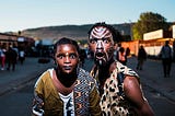 Two aborigines with painted faces stare with amazement.