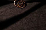 two gold wedding bands on a black cloth