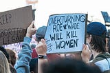 Pro-choice protest signs raised over the heads of demonstrators