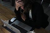 woman sitting looking stressed while staring at her computer at work