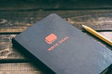 Black notebook labelled Write Ideas and a pencil on a wooden table