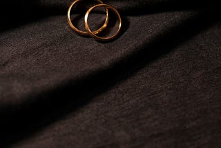 two gold wedding bands on a black cloth