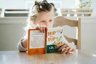 Dr seuss book with a young girl reading hop on pop