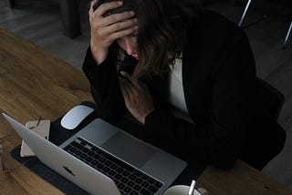 woman sitting looking stressed while staring at her computer at work