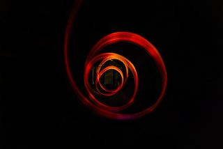 A vibrant red cloth twirling like a spiral before a black background