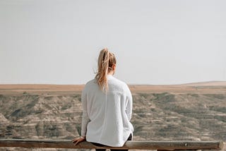 Young woman sitting on a split rail fence