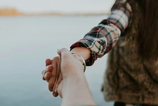 female person walking away from someone whose hand she is holding