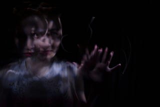 A blurry and distorted image of a woman reaching through the dark