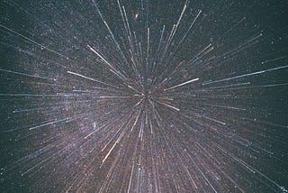 A display of streaks of light radiating from a central point, resembling a burst of fireworks or a meteor shower.