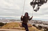 Alice (the author) looks towards the city as she swings on an epic wooden swing.