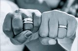 Two married people bumping fists sideways, showcasting their rings