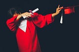 Female university graduate in a red gown, red cap, doing a dab, on a pure black background.