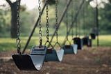 A series of empty swings at a park