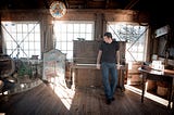 Gentry Bronson standing in front of the upright piano at Nick’s Cove in Tomales Bay, California