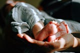 A newborn baby’s feet cradled in a mother’s hand.