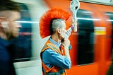 Man with orange mohawk next to train.