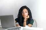 A serious ethnic young woman using a laptop at home