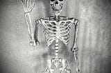 Grungy looking image of a human male skeleton with one arm raised like he is waving HI set against a black & white grainy backgound.