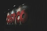 Image of a lit up Costco sign in the darkness.