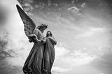 statue of an angel and young woman under cloudy skies