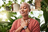 woman smiling gently with eyes closed and hands folded over her heart