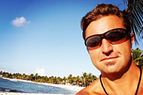 Gentry Bronson shirtless and wearing sunglasses on a surf beach in Mexico