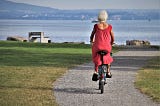 Image of pensioner wearing red dress & riding a bike by pasja1000 on Pixabay