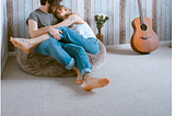 couple snuggling on bean bag with guitar nearby