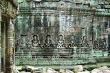 Temple wall, covered in sitting Buddhas and green lichen